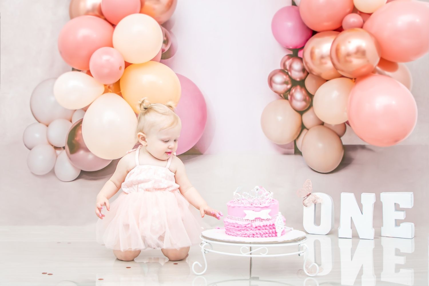 baby girl's 1st year cake smash photo with balloon backdrop