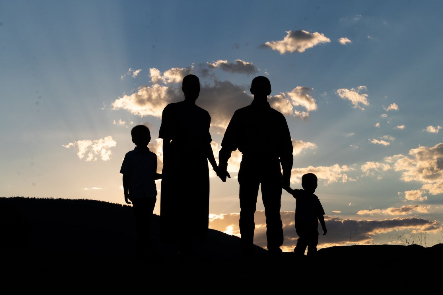 silhouettes of parents and kids standing at sunset