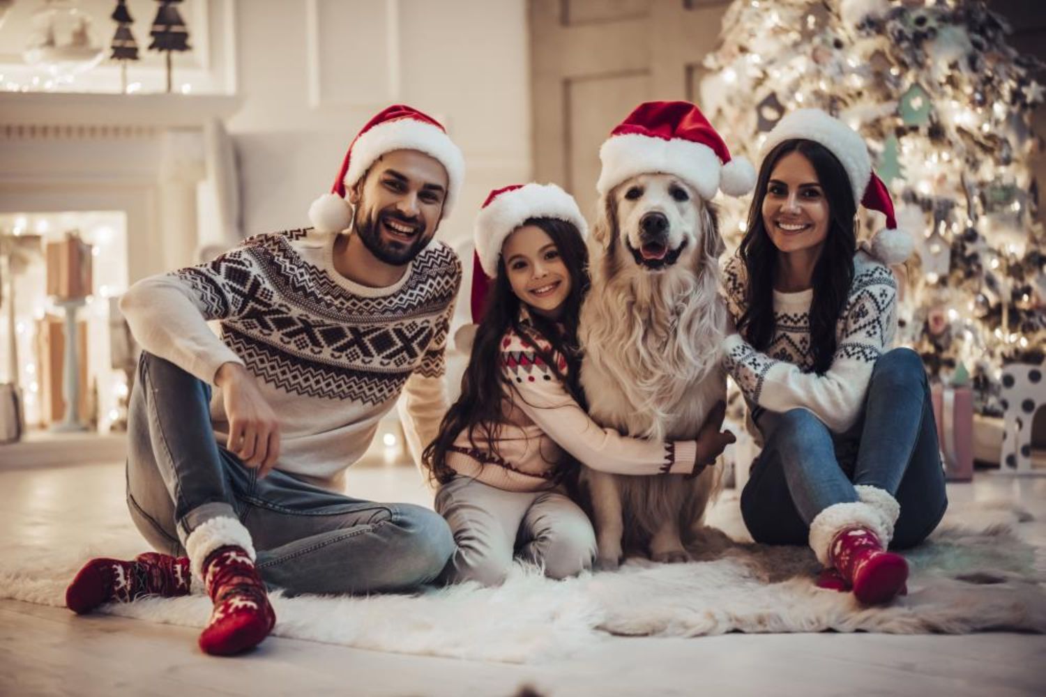 family taking photo with their dog by snuggling together in front of lighting Chritmas tree 