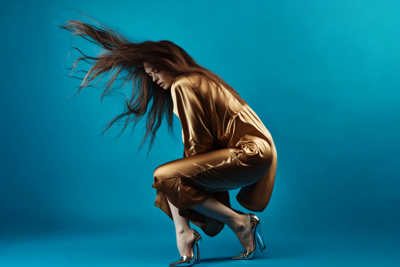 Fashion model in a golden dress striking a dynamic pose on a blue background.