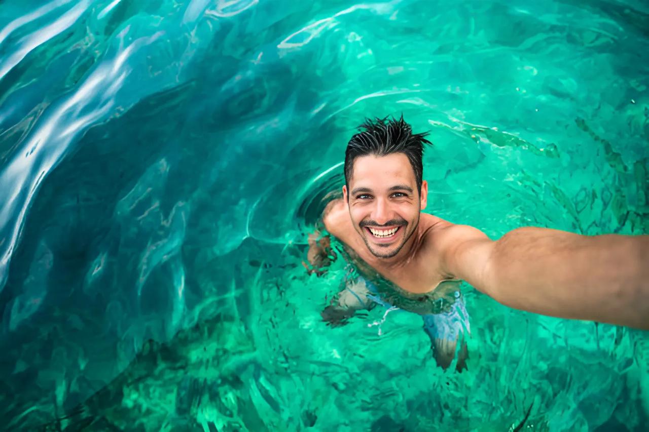 A man is taking a  phone selfie in an ocean