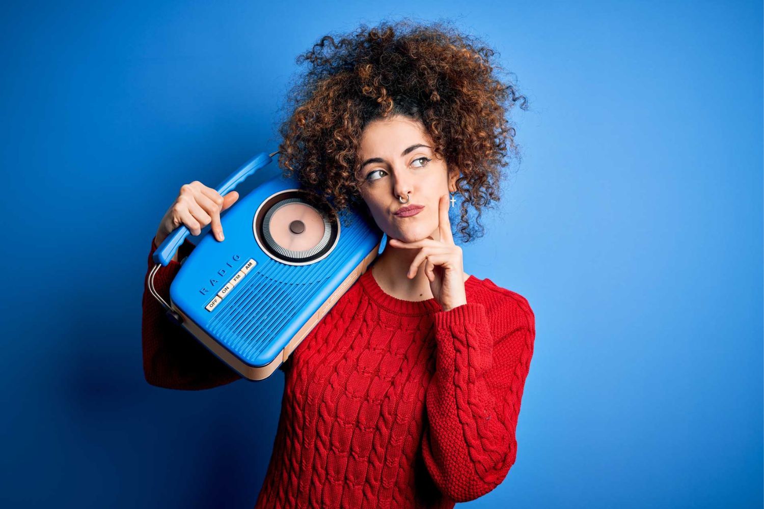woman holding blue vintage radio on shoulder 