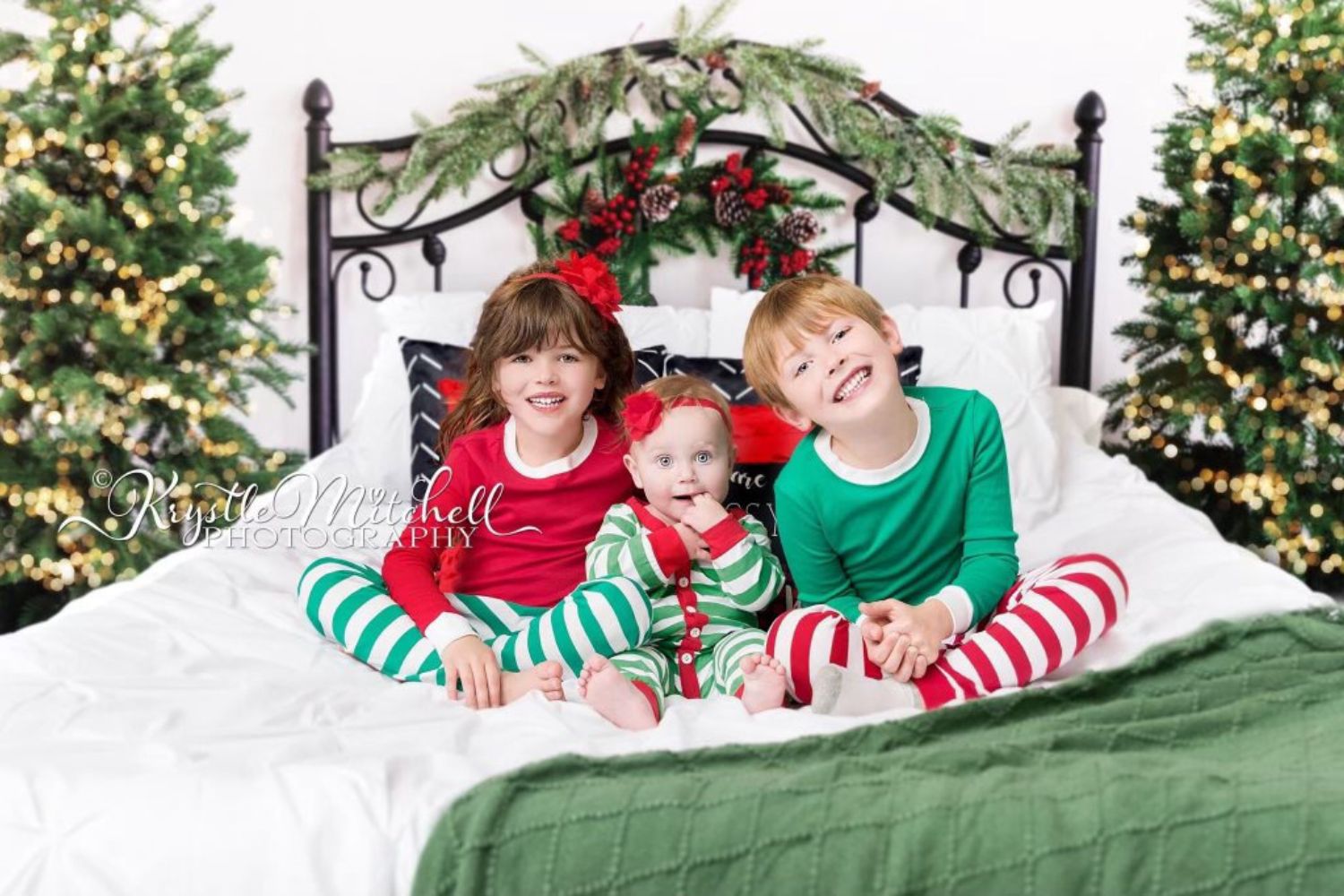 siblings sitting on bed with Christmas pajamas