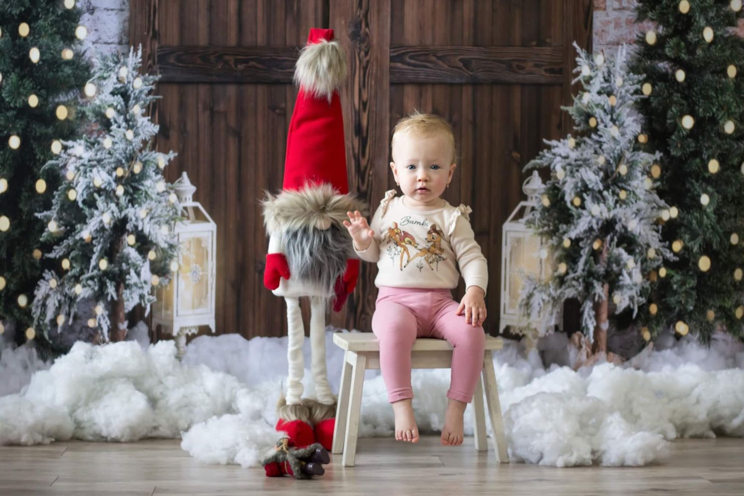 little girl taking a sitting photo with Christmas trees