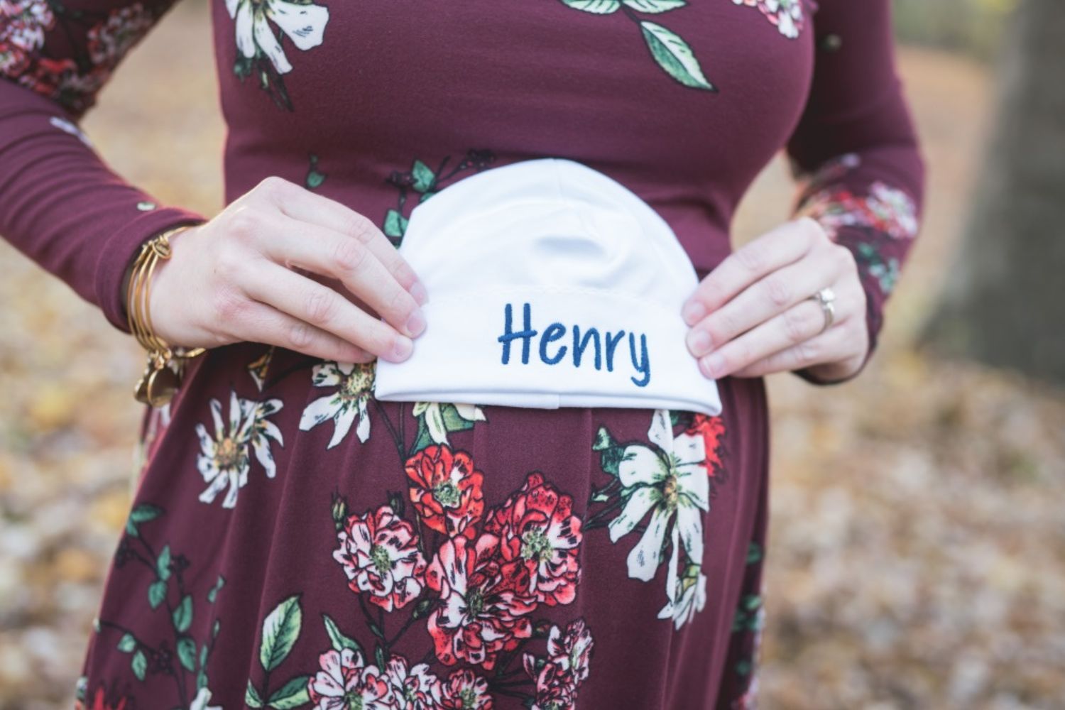 maternity photo by holding a baby cap with name on