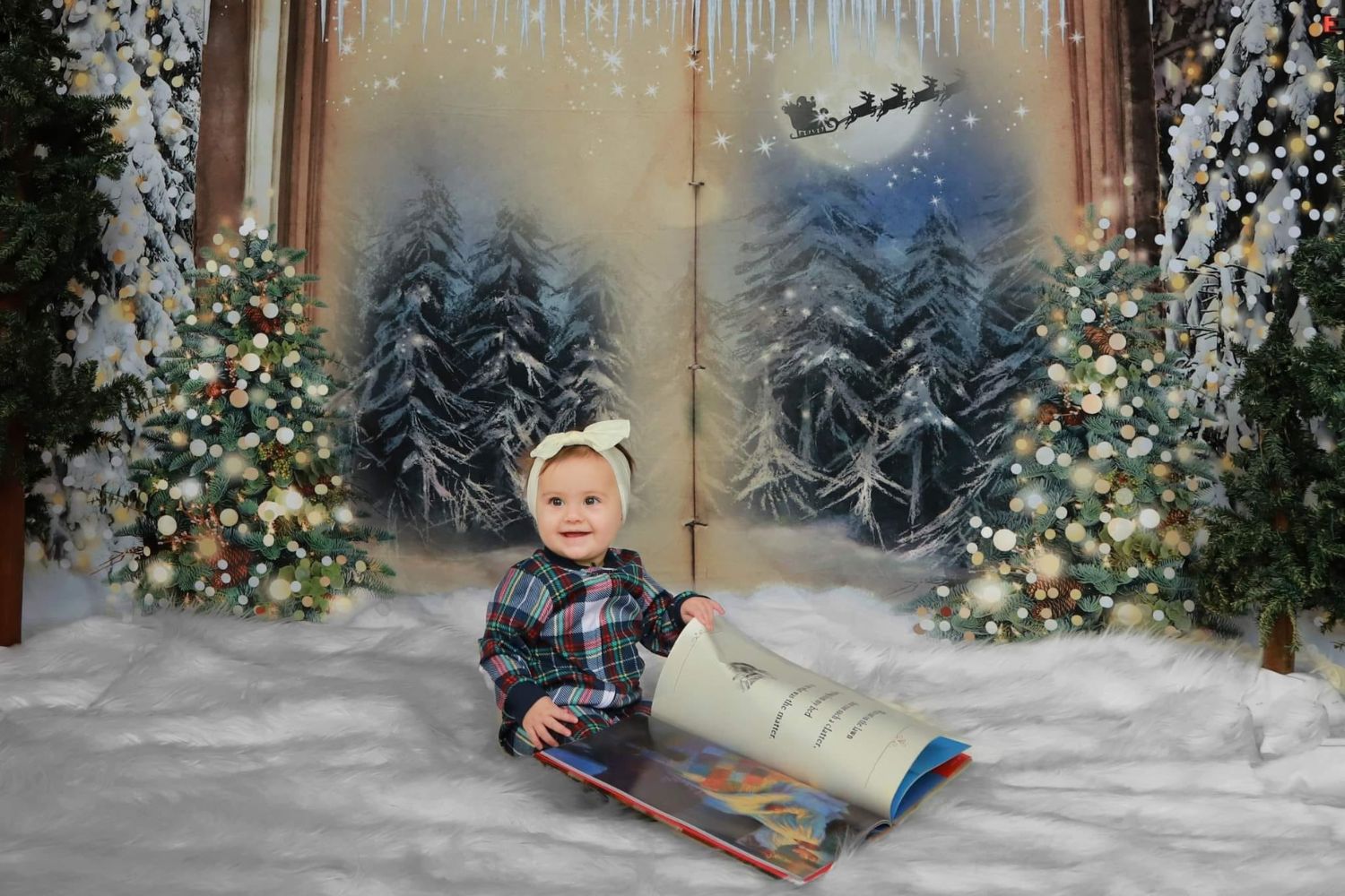 a baby girl reading a big book in front of a fireplace