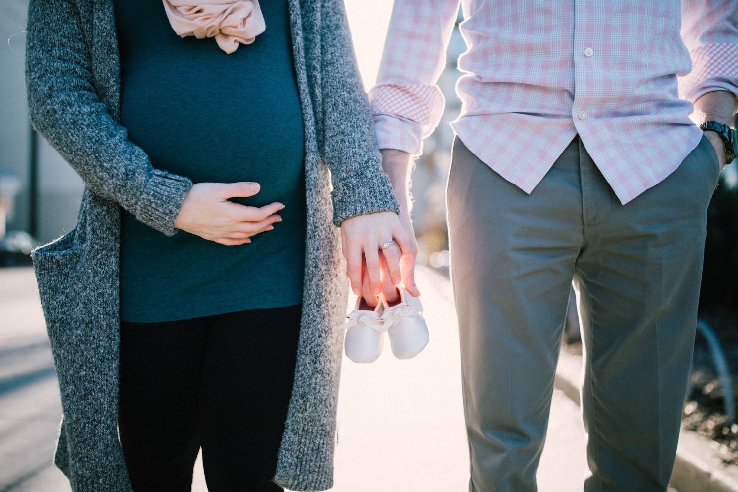 couple maternity photo by holding the baby's tiny shoes