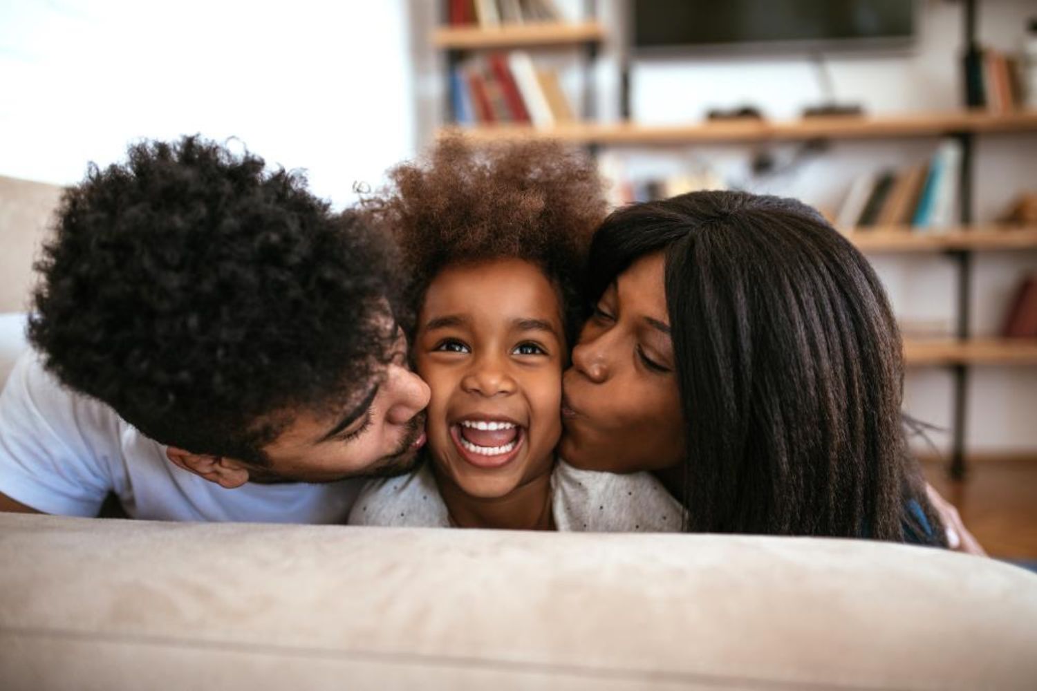 mum and dad kissing their kid on cheeks