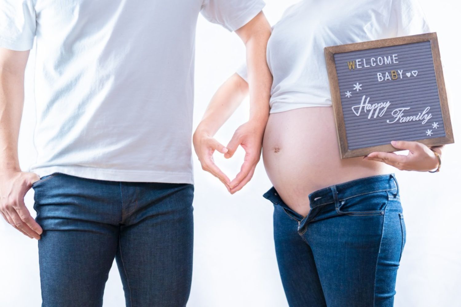 couple maternity photo by holding a written board
