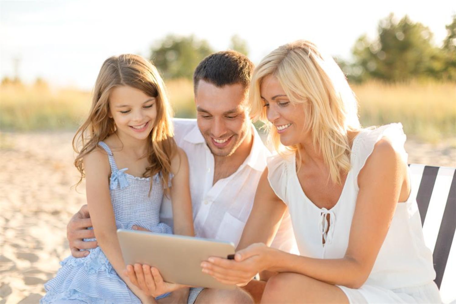 family looking at ipad on beach in white and blue