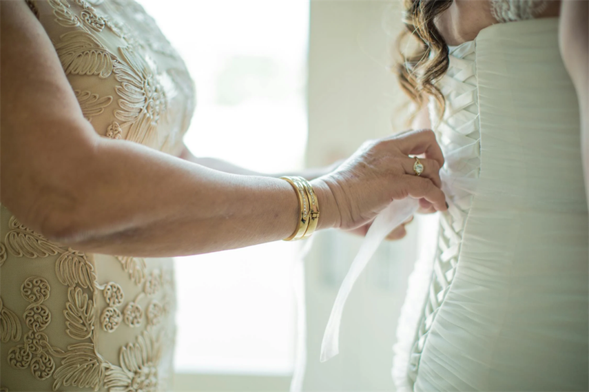 Mother is helping the bride adjust her wedding dress