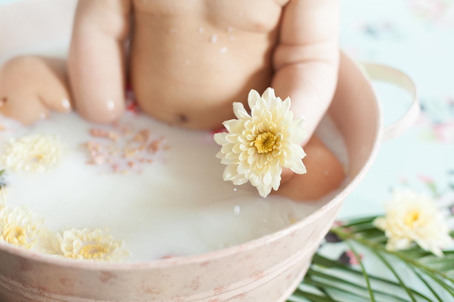 baby holding a flower in milk bath