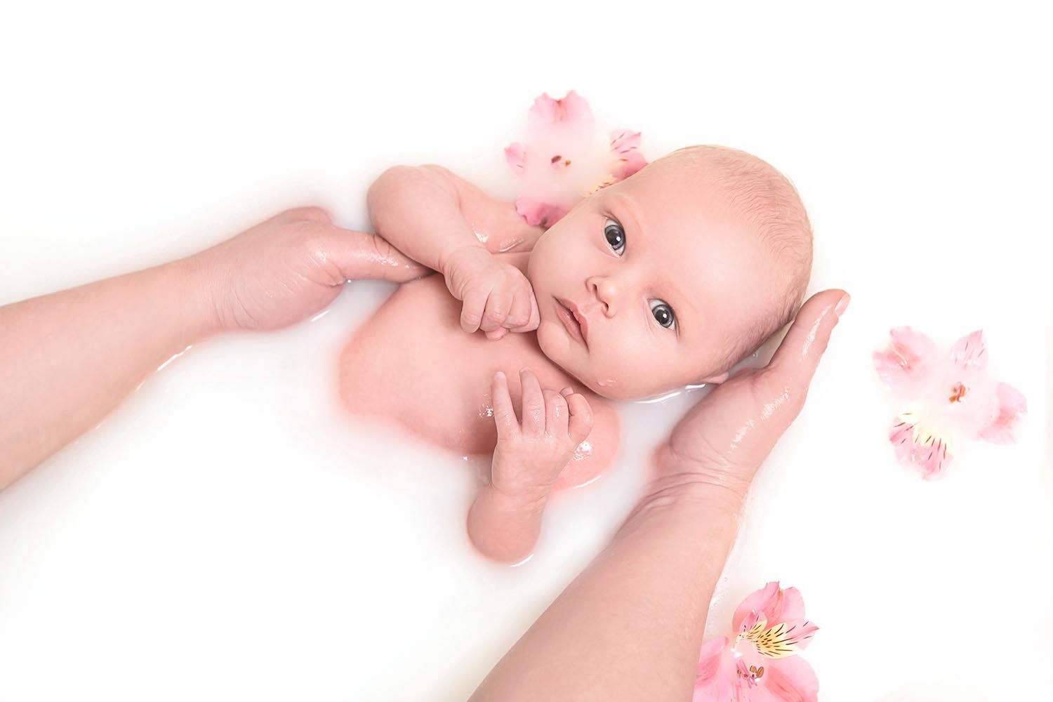 baby lying in milk bath by holding under head