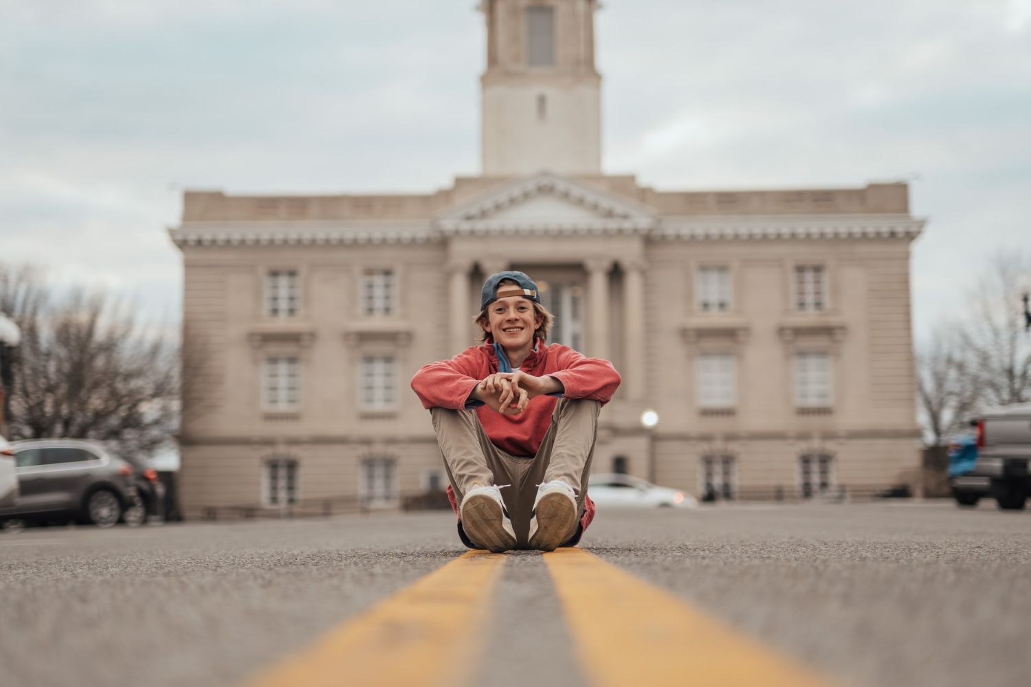 senior boy photo by sitting in front of a building 
