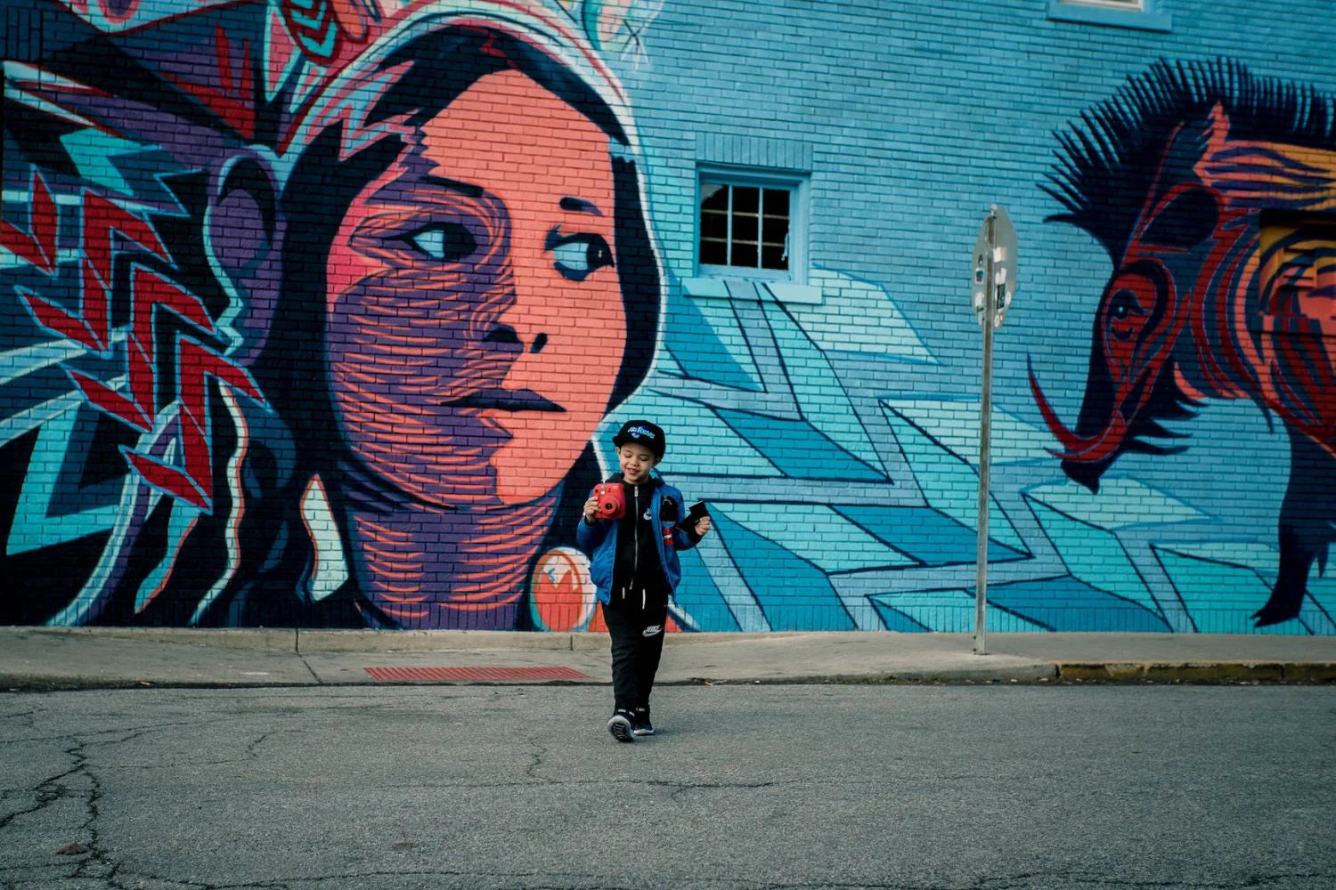 photo of boy using polaroid camera in front of a Graffiti wall