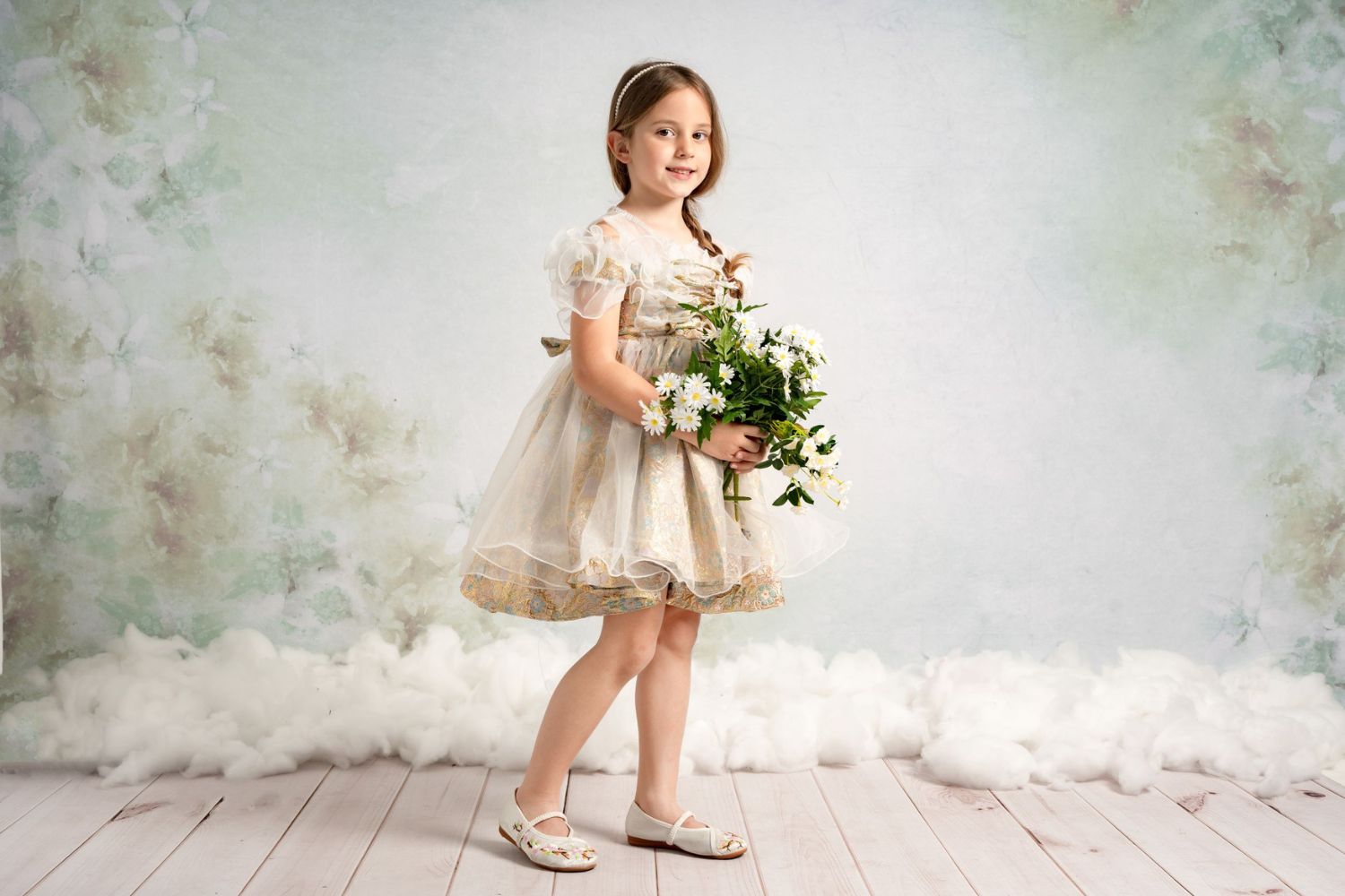 little girl holding a bunch of flower and standing in front of a flower background
