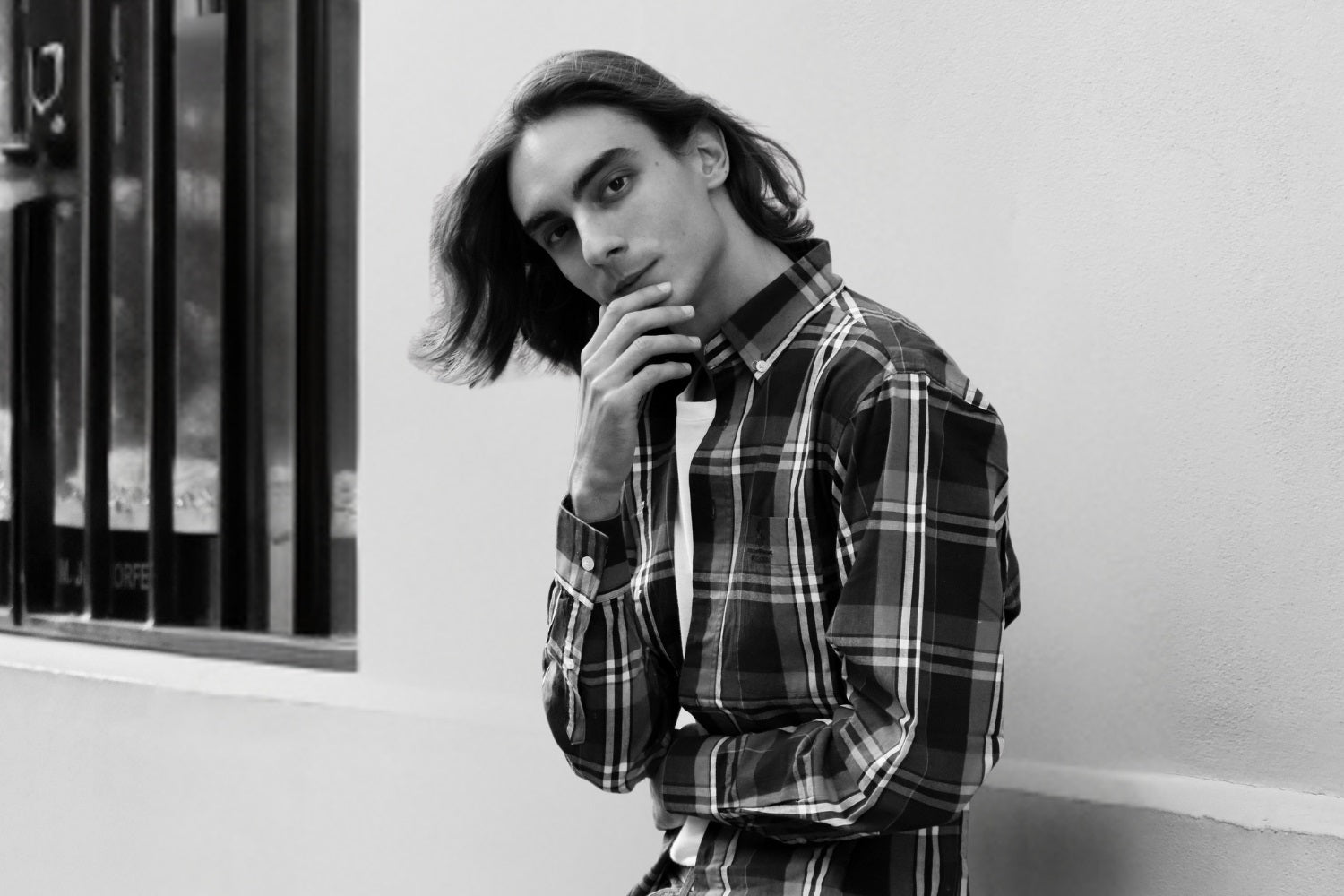 A classic male portrait pose that a man is staring at the camera and smiles with his hands on his chin.