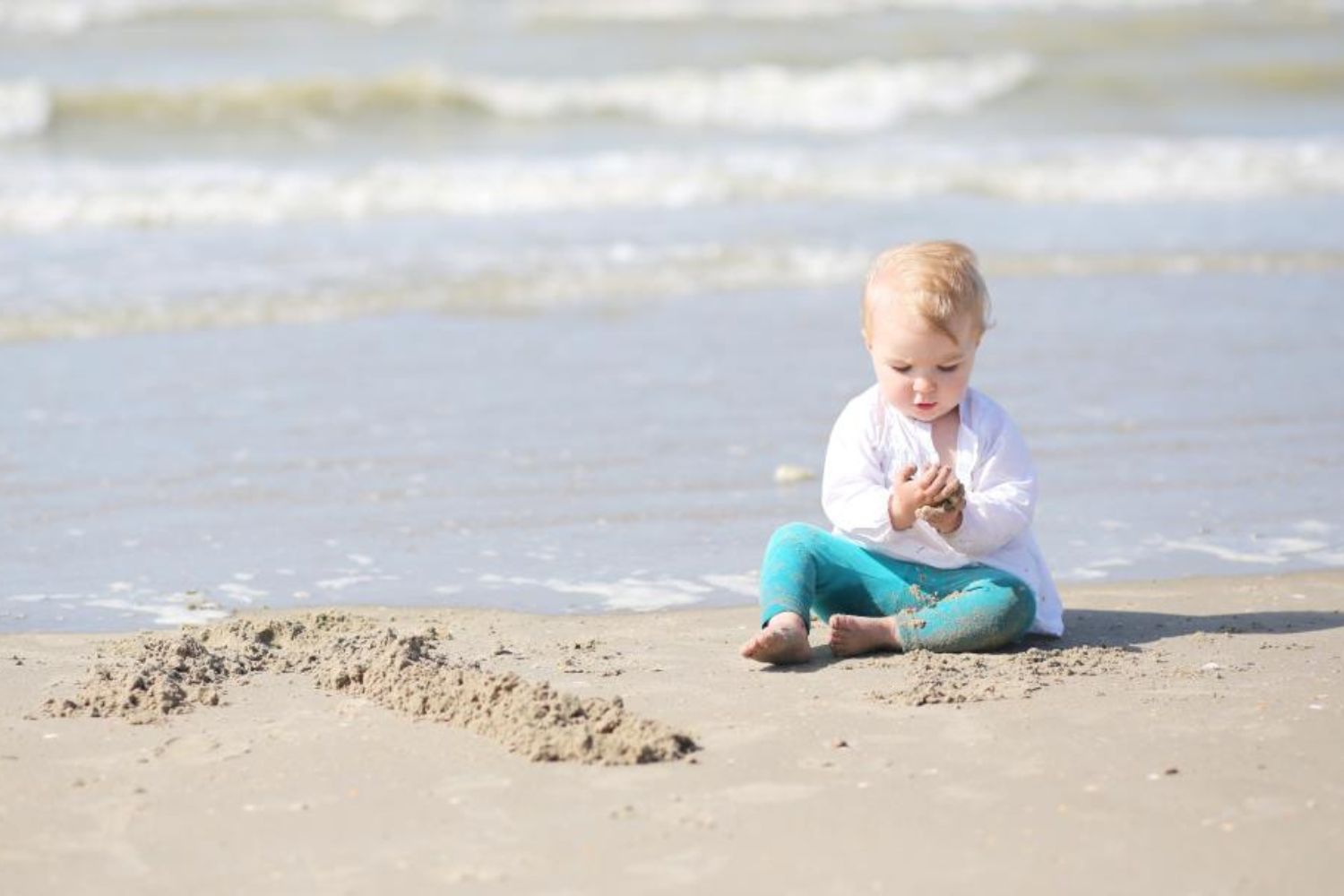 baby boy sitting at beach and playing sands