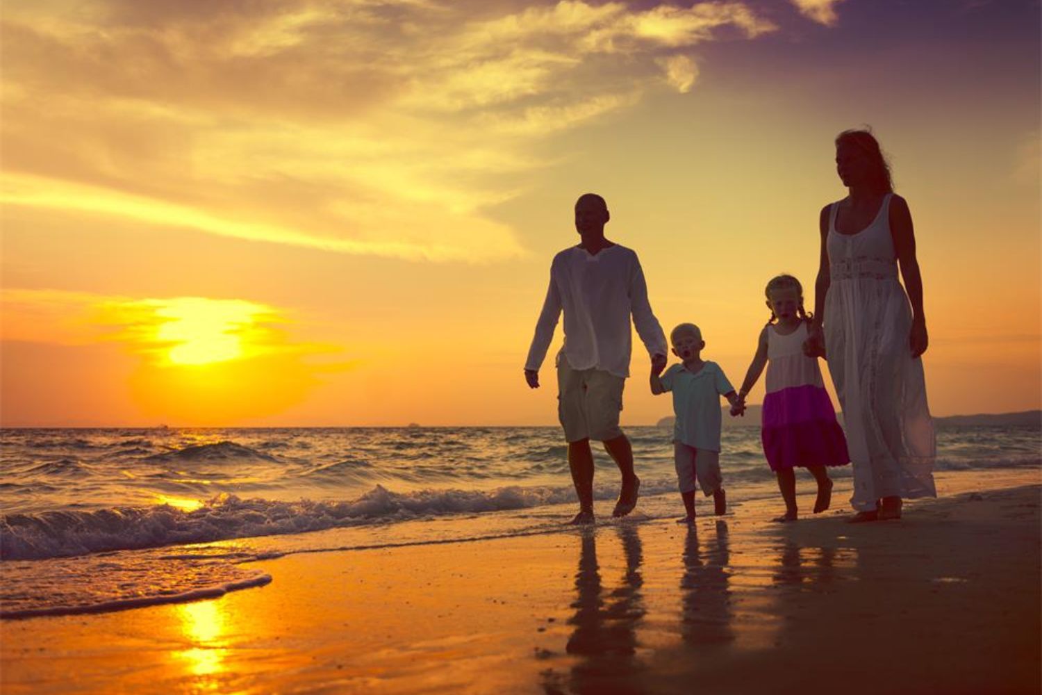 family holding hands and walking on beach in sunset