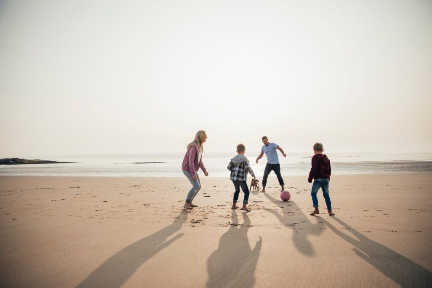 family playing football on beach 