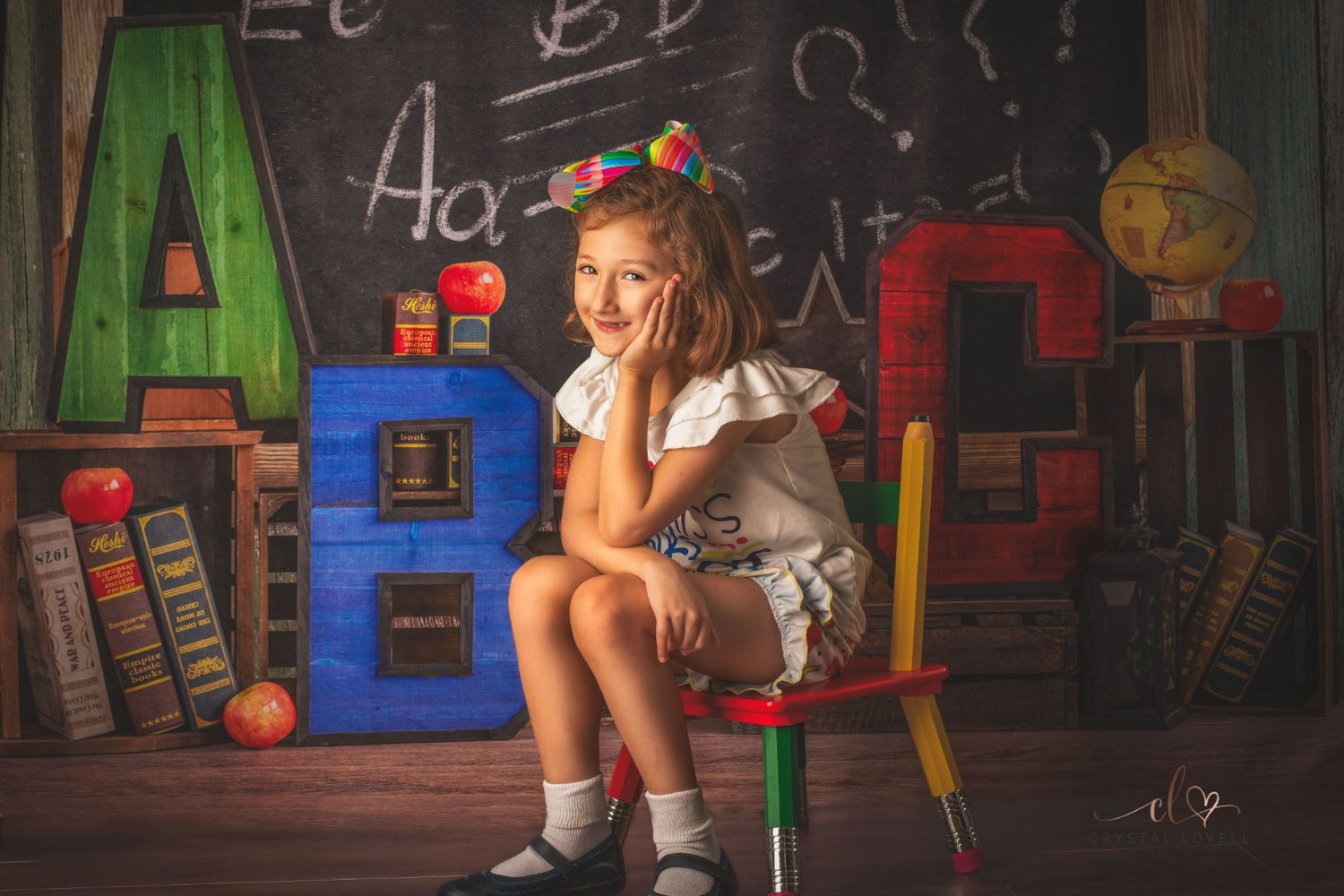 a little girl sitting on chair with blackboard