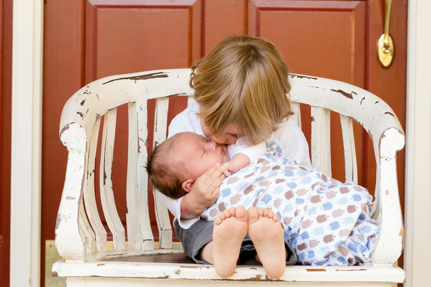 The brother is kissing his little brother.