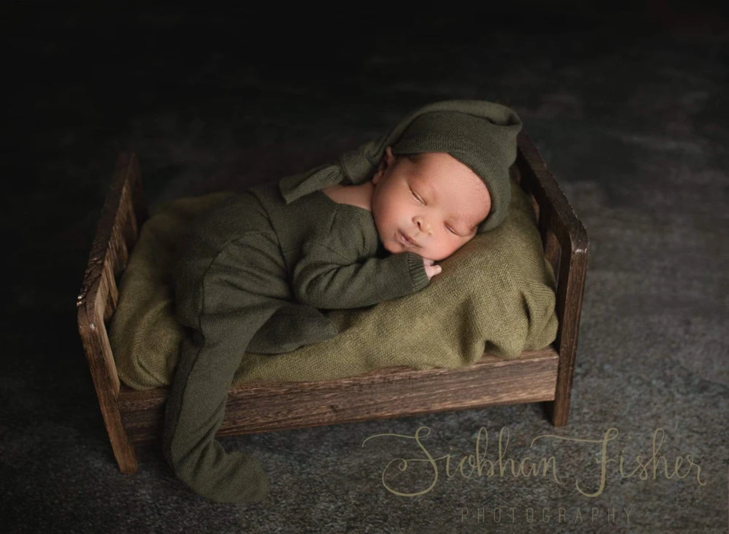 A baby lies down in a wooden bed