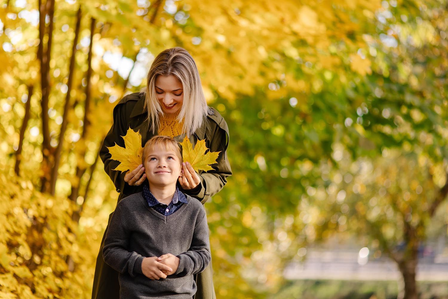 mom and son playing yellow leaves in the forest