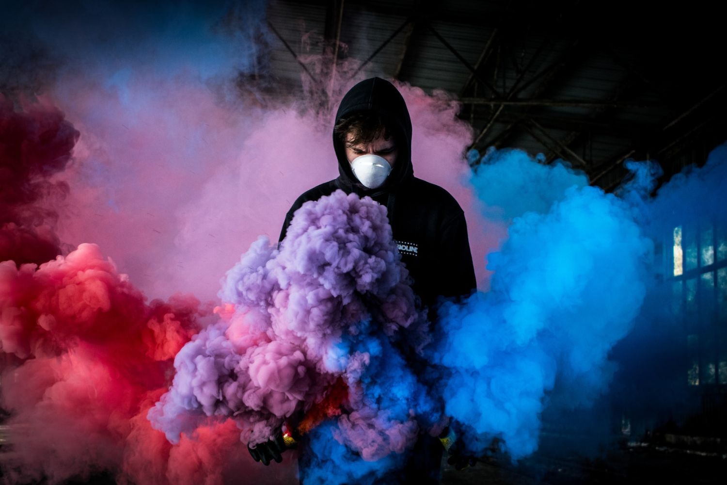 person in the middle of colorful smoke bomb 