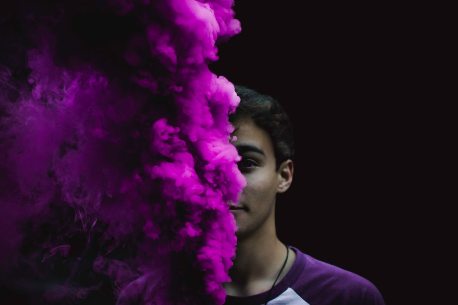 a  male portrait behind a purple smoke bomb