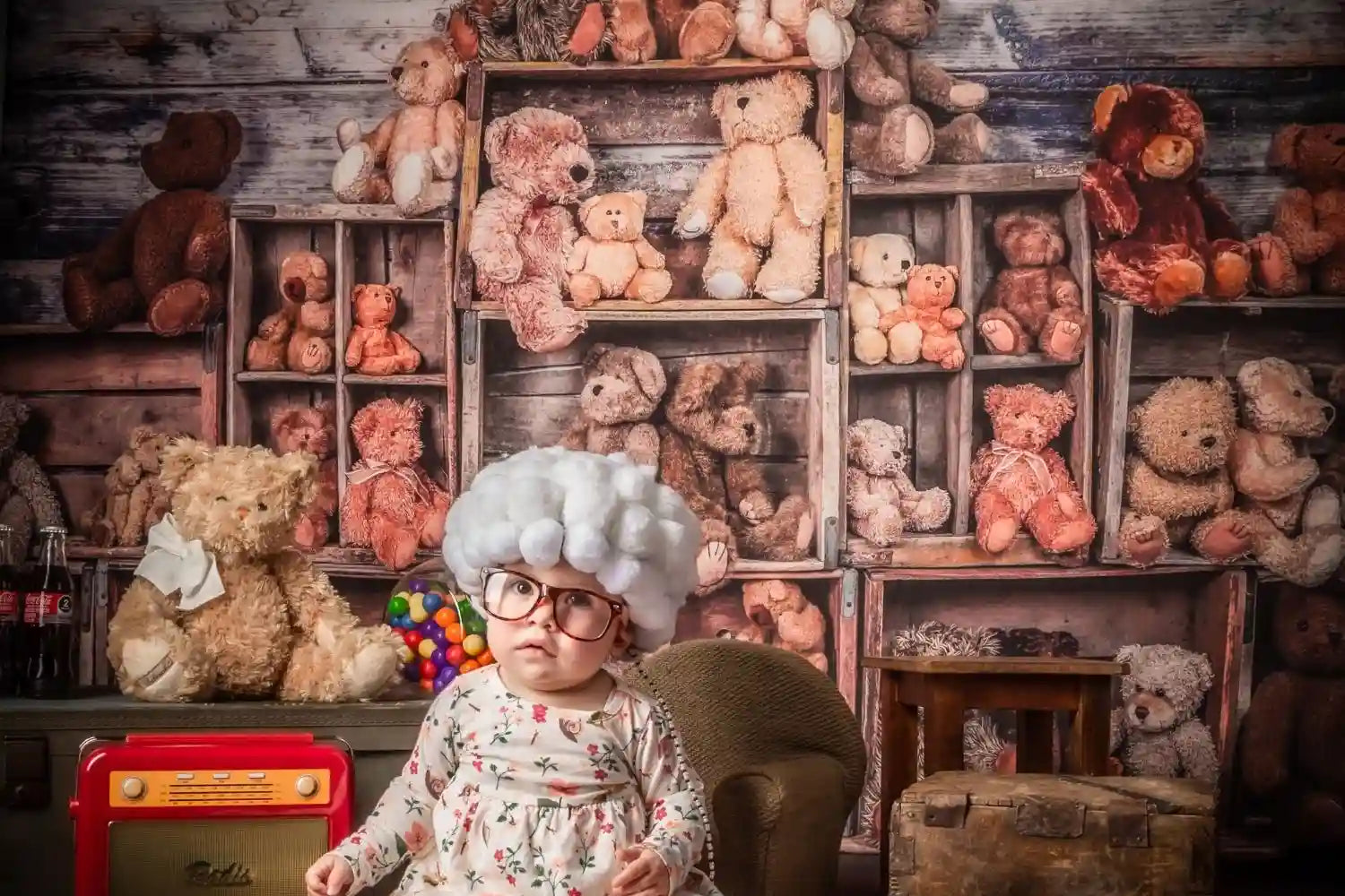 A  child sit in front of background wall full of stuffed bears