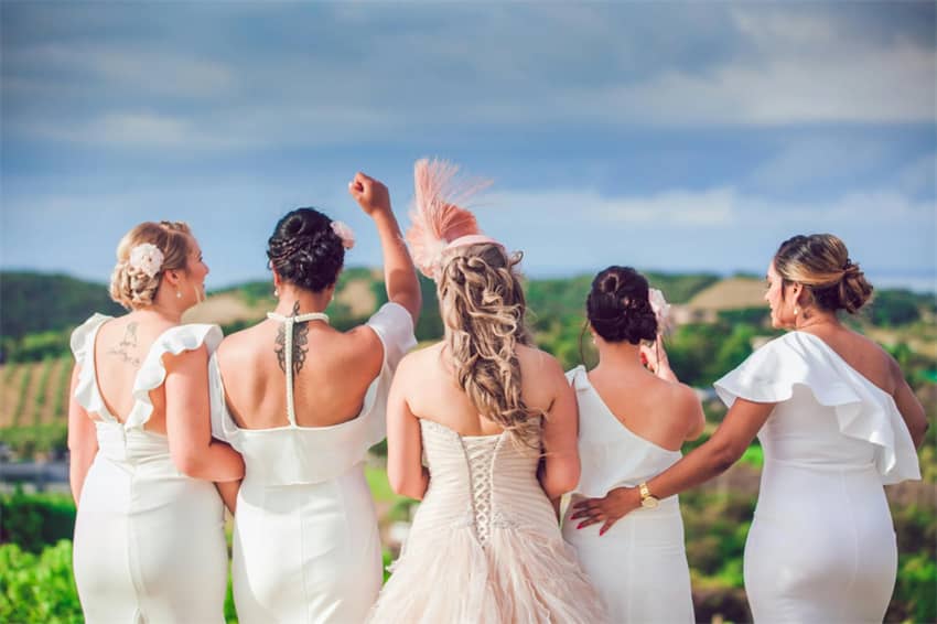 Bride and bridesmaids enjoy a scenic view in matching dresses.