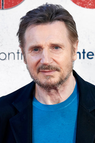 liam neeson with beard and blue tshirt and jacket