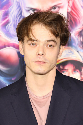 Actor Charlie Heaton with back board wearing blue jacket and pink tshirt