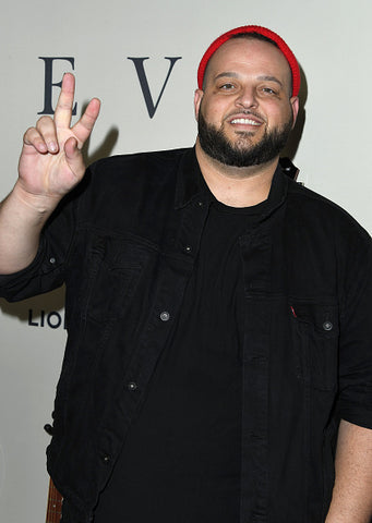Daniel Franzese on red carpet in red hat and V sign