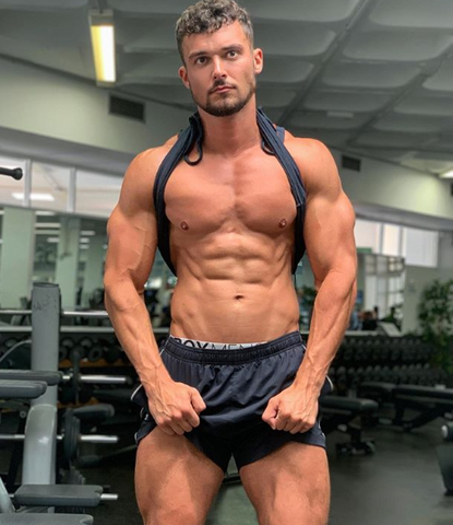 Box model flexes his muscles in black shorts