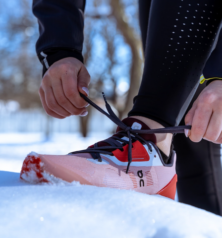 runner tying up pink shoes in the snow