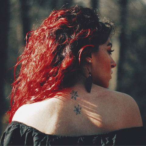 Woman with bright red curly hair and turned to the side.