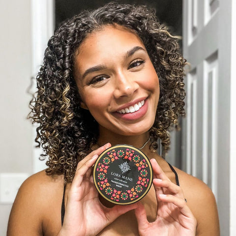 Woman with curly hair holding Loba Mane's Transformative Hair Mask.
