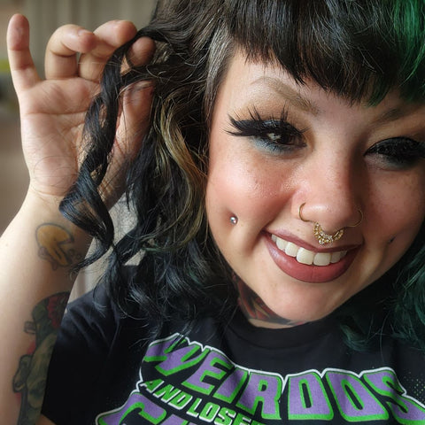 Woman with green split-dyed hair and bangs, showing her curl ringlet created using Loba Mane's Styling Cream.
