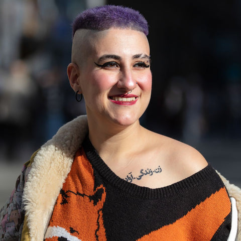 Person with short purple hair and the sides of their head shaved smiling.