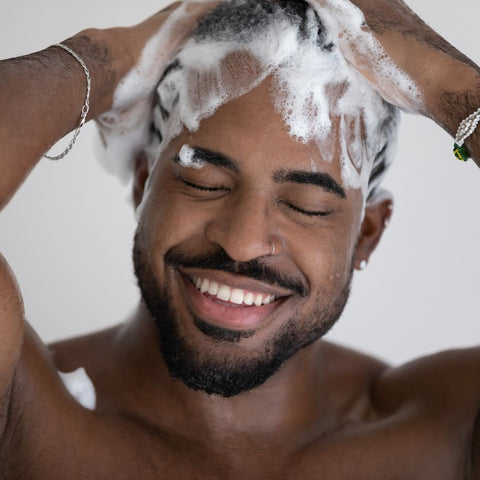 Man washing his hair with shampoo and smiling
