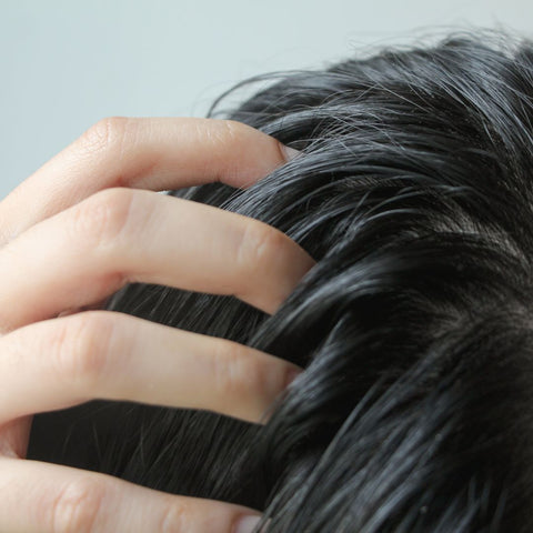 Upclose image of someone touching their scalp.