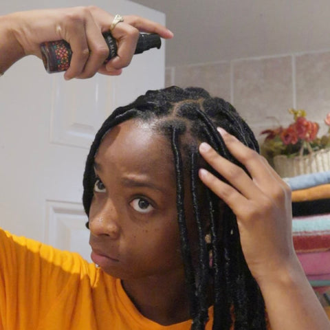 Woman applying Loba Mane's Illuminating Hair Oil to her scalp.