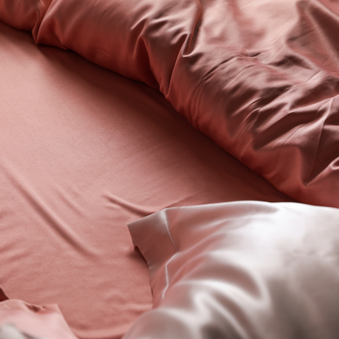 Silk pillowcases placed onto a bed.