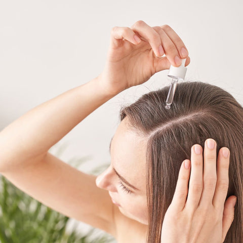 Woman applying hair oil to her scalp.