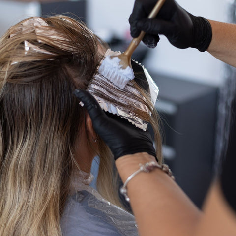 Person getting their hair dyed at a hair salon.