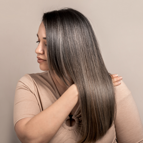 Woman with shiny straight hair holding her.