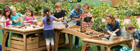 An photo of children playing at an outside crafting station with various materials