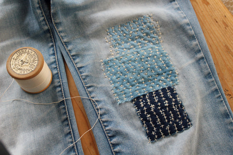 a pair of denim being patched with other denim pieces